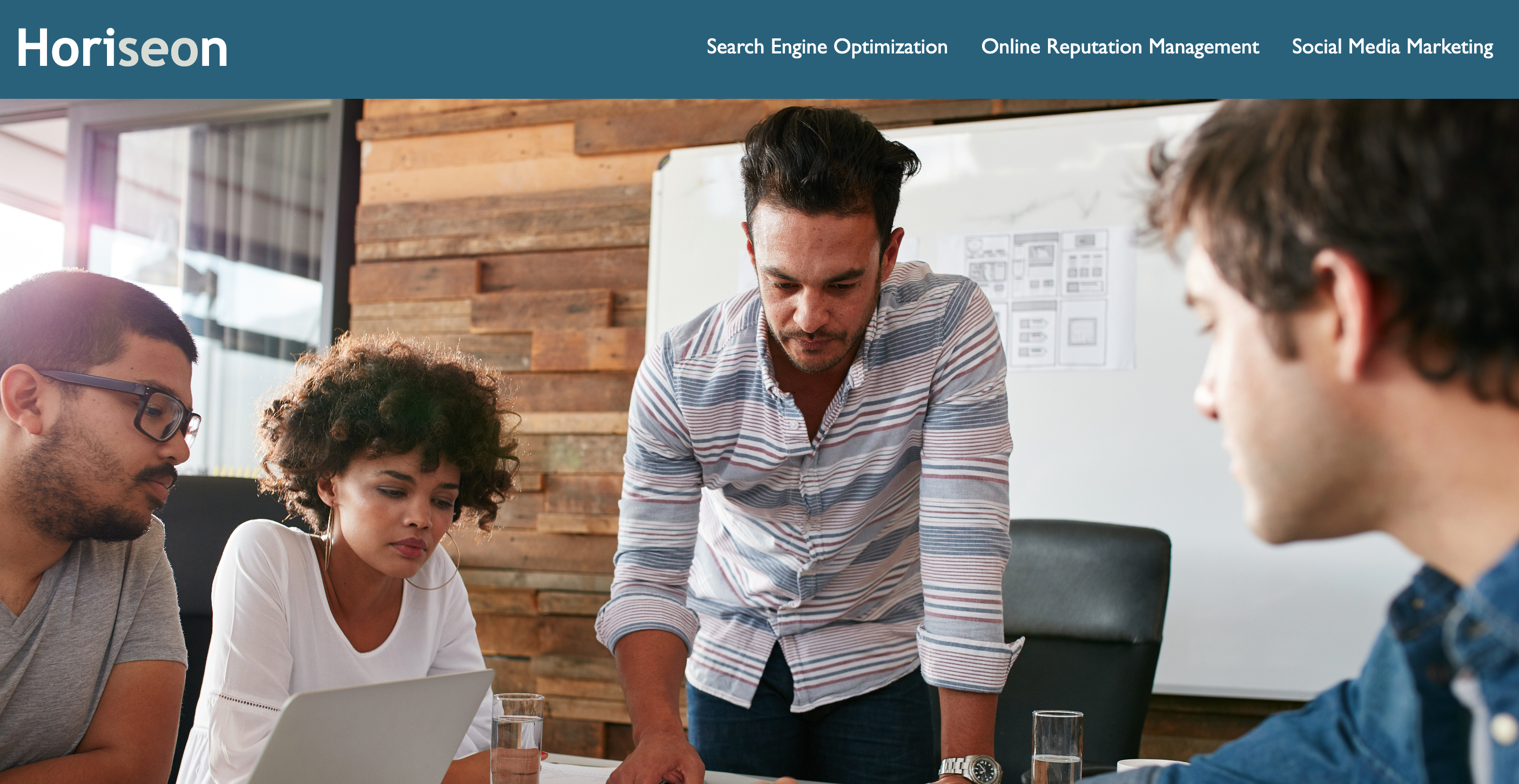 A website screenshot, with a group of people collaborating around a table